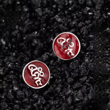 Round red earrings with silver intricate designs on black textured stones background