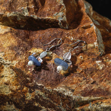 Handmade silver earrings with blue stone, clear quartz, and pearl on rusty rock background