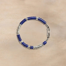 Blue and silver beaded bracelet with metal clasp on beige surface