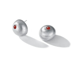 Modern silver stud earrings with round red gemstone center on white background