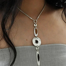 Silver abstract pendant necklace on a woman wearing a gray strapless top with black hair