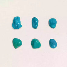 Six small polished blue turquoise stones on a white background in two rows