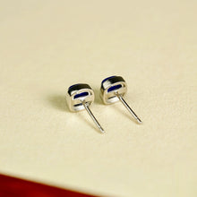 Close-up of silver stud earrings with blue inlay on beige surface