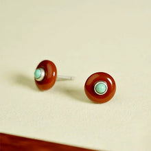 Round stud earrings with brown outer ring and small turquoise center on light background