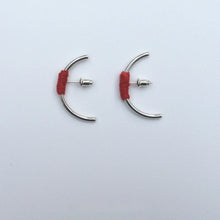 Pair of silver half hoop earrings with red thread wrapped detail on white background