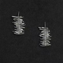 Pair of modern silver wire earrings with stacked irregular horizontal bars on black background