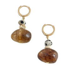 Gold hoop earrings with brown marbled stone and black and white spotted bead charms
