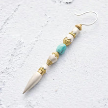 Elegant white and turquoise beaded dangle earring with gold accents on white textured surface