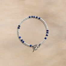 Silver and blue beaded bracelet with toggle clasp on beige background