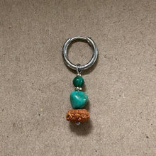 silver hoop earring with green and turquoise beads and a brown textured bead on beige background