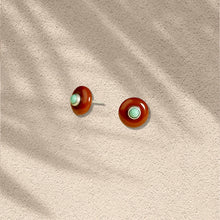 Round stud earrings with brown outer rings and turquoise center stones on textured beige background