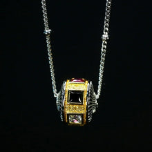 Silver and gold beaded pendant necklace with black and clear square gemstones on black background