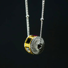 Silver and gold pendant with black, red, and clear gemstones on a silver chain