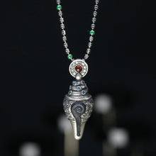 Silver pendant necklace with spiral design and multicolored gemstones against black background