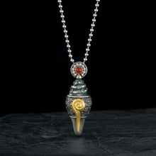 Intricate silver pendant necklace with blue gems, red stone, and gold spiral detail on black background