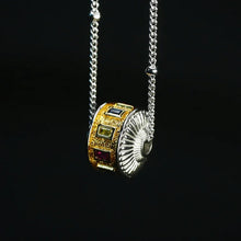 Close-up of gold and silver pendant necklace with colorful gemstones on silver chain