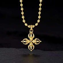 Gold pendant cross with intricate designs and black stone center on beaded gold chain