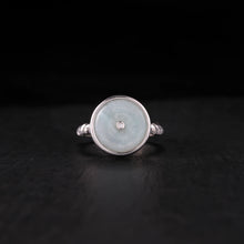 Silver ring with round pale blue jade centerpiece and small diamond on black background