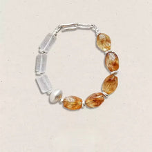 Handcrafted bracelet with amber and clear quartz beads on a beige background