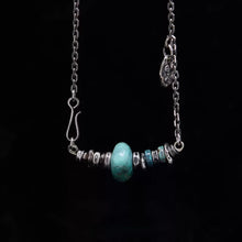 Silver chain necklace with turquoise and silver beads on black background