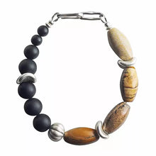 Handmade bracelet with black round beads, mixed brown stone beads, and silver accents on white background