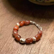 Close-up of polished orange agate and silver beads bracelet on wooden surface