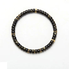 Black and gold beaded bracelet with metallic and polished round beads on white background