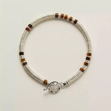 silver coil bracelet with brown and black beads and toggle clasp on white background