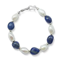 Elegant bracelet with alternating white pearls and deep blue lapis lazuli stones on white background