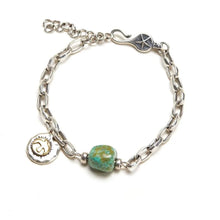 Silver chain bracelet with turquoise bead and round charm featuring star and sun designs