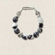 Black and white beaded necklace with silver clasp and mixed stone beads on beige background