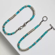 Silver and turquoise beaded bracelet with toggle clasp on white surface