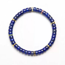 Round lapis lazuli beaded bracelet with gold and gemstone spacer accents on white background