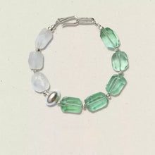 Bracelet with faceted green and white beads and silver clasp on light background