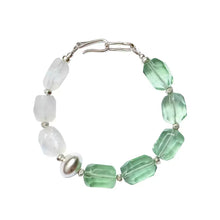 Bracelet with alternating translucent green and white faceted beads and silver accents on white background