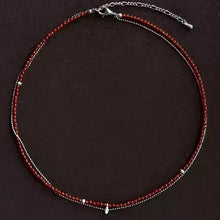 Delicate double-layered necklace with small red and silver beads on dark background