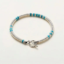Silver and turquoise beaded bracelet with toggle clasp on white background