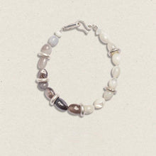 Elegant beaded bracelet with mixed white and gray stones and silver accents on neutral background