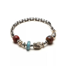 Silver chain bracelet with turquoise, red, and textured silver beads on white background