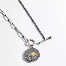 silver necklace with textured pendant featuring a gold-tipped pyramid design on mixed metal chains