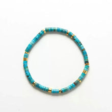 Turquoise and gold beaded stretch bracelet on white background