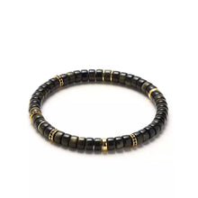 Black and gold beaded bracelet with cylindrical styling on white background