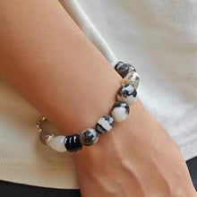 Close-up of wrist wearing a black and white marbled bead bracelet on light skin