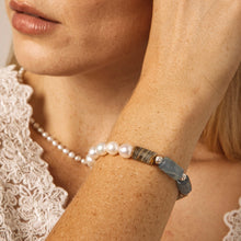 Close-up of woman wearing pearl necklace and gemstone beaded bracelet with blue and brown stones