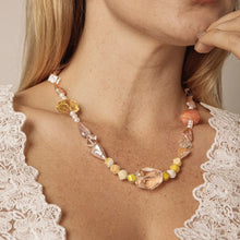 Close-up of woman wearing beaded necklace with multicolor gemstones and pearls on lace top