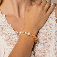 Close-up of wrist wearing pearl and amber bead bracelet on lace-trimmed white top