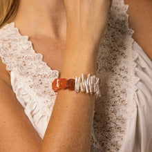 Woman wearing a natural stone and pearl bracelet with red jasper and white freshwater pearls