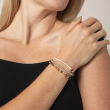 Close-up of woman wearing three beaded bracelets with pearls and natural stones on wrist
