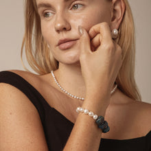 Woman wearing elegant pearl jewelry including necklace, bracelet with pearls and blue stones, and pearl earrings