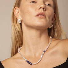 Close-up of woman wearing handmade pearl and blue stone necklace and matching pearl earrings